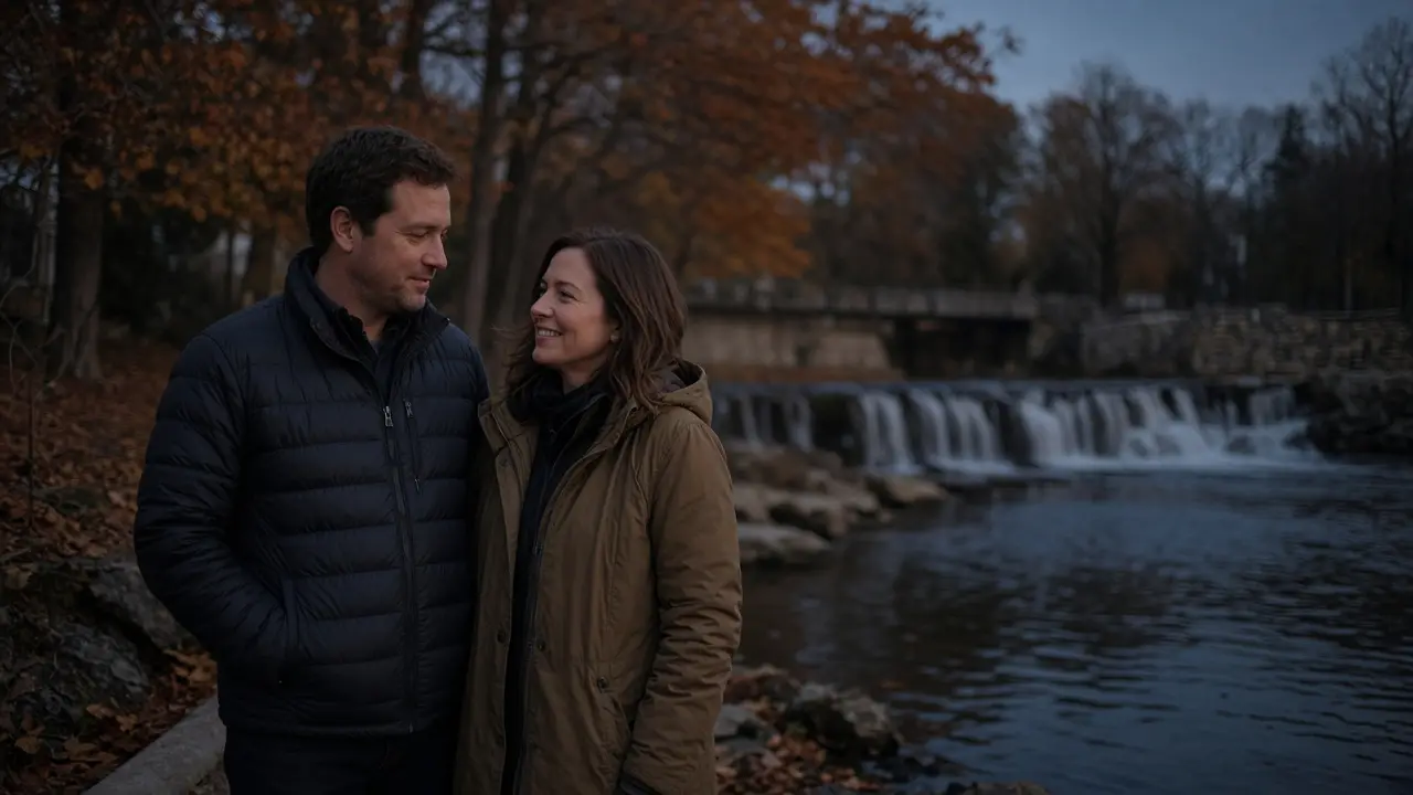 A dressed couple in jackets beside a small river at dusk, autumn trees.
