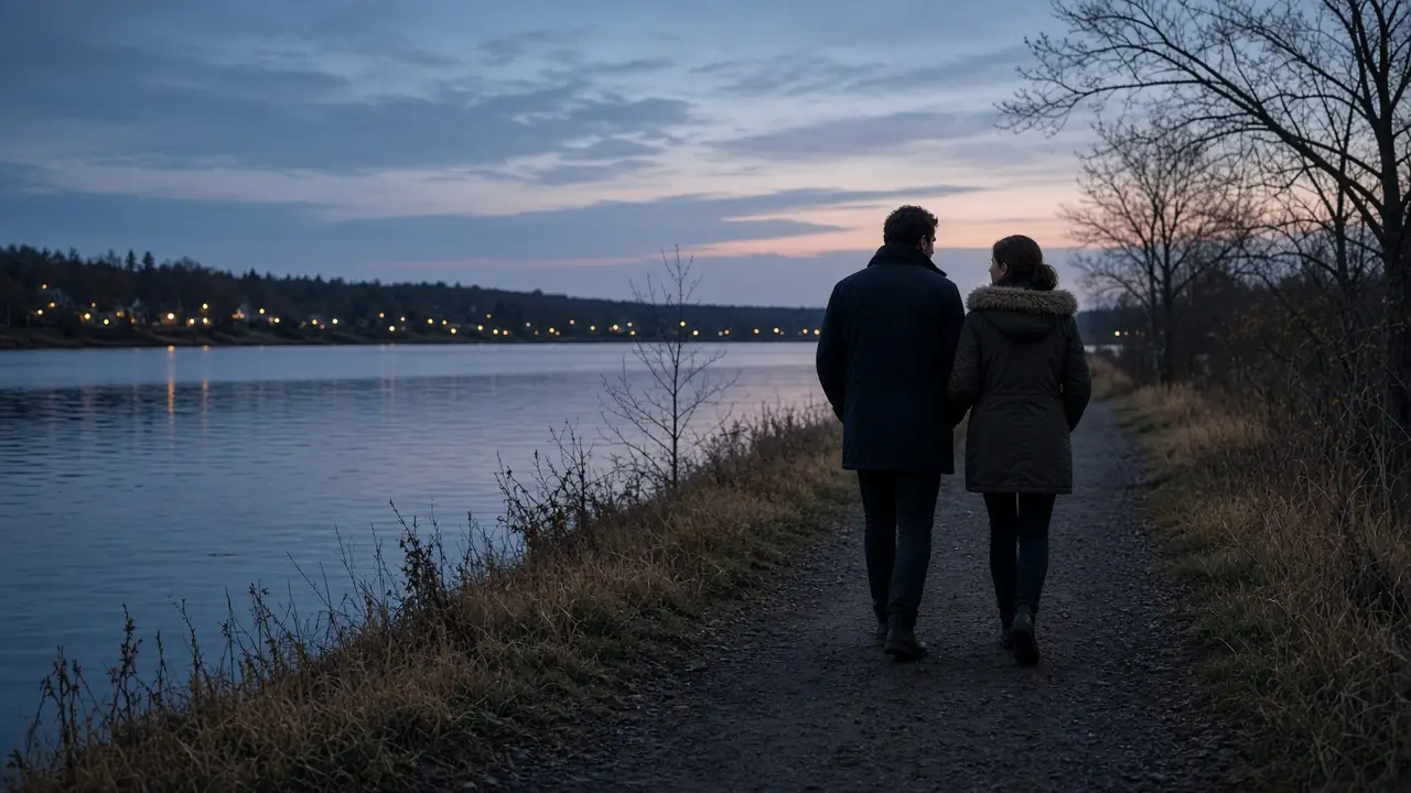 A dressed couple in coats beside a lake at dusk, a distant shoreline.