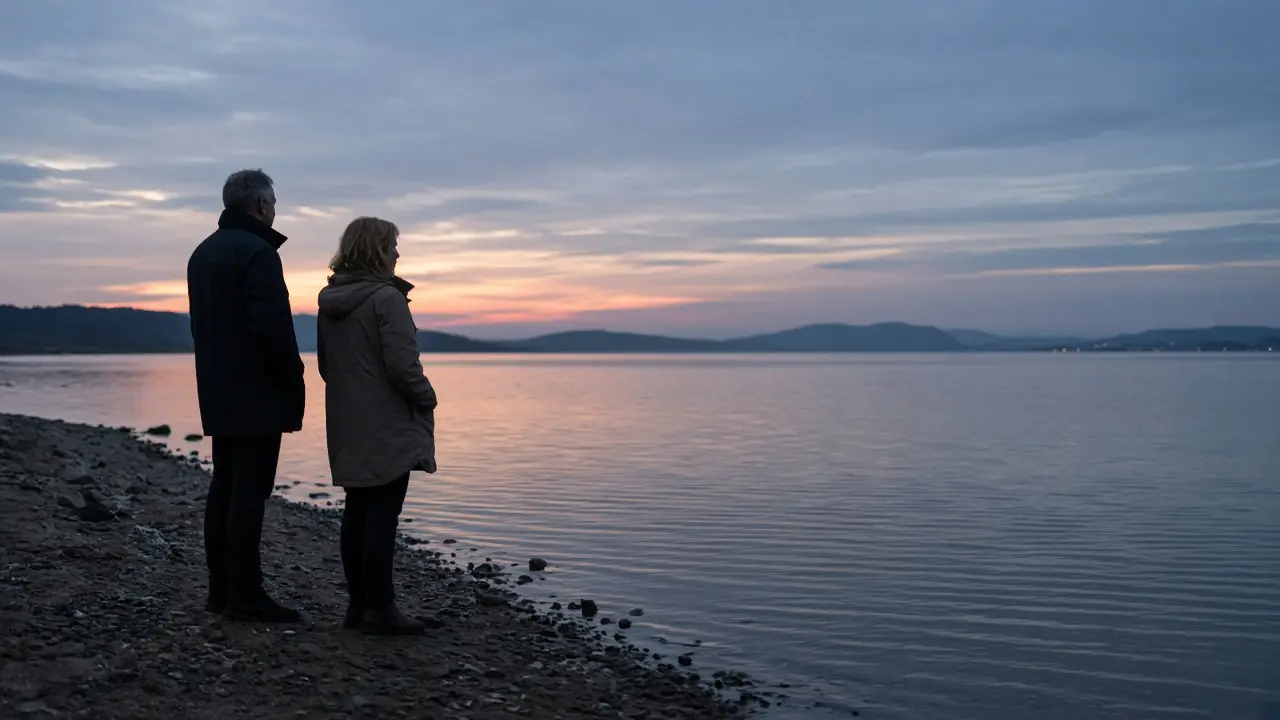 A dressed couple in coats beside a lake at dusk, no signs.