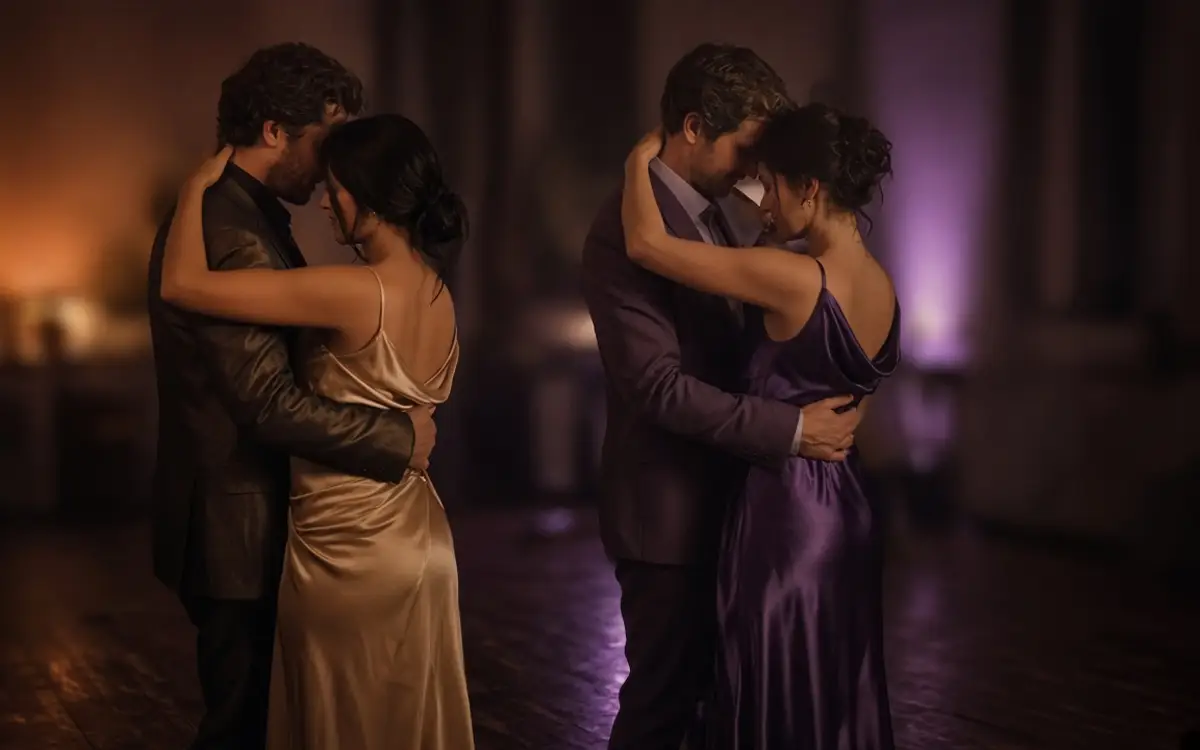 Two dressed couples dancing close on a small dark floor.